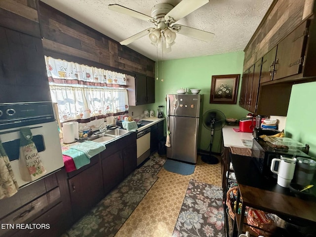 kitchen featuring a sink, a textured ceiling, white appliances, light countertops, and ceiling fan