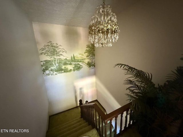 staircase featuring a notable chandelier and a textured ceiling