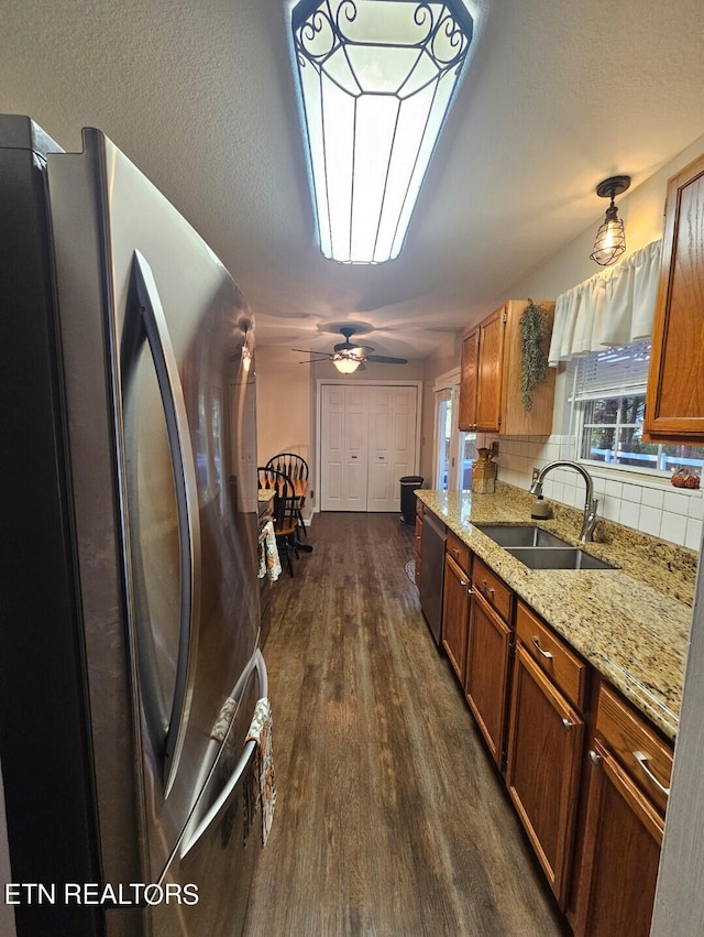 kitchen with dark hardwood / wood-style flooring, ceiling fan, backsplash, sink, and stainless steel appliances