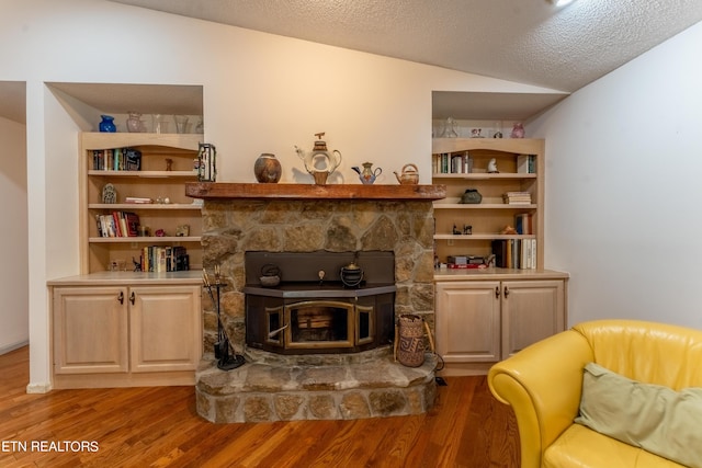 living area featuring lofted ceiling, hardwood / wood-style floors, and a textured ceiling