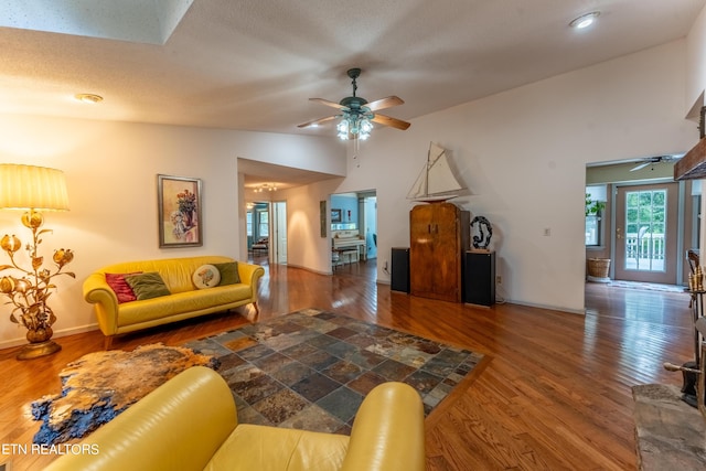 living room featuring ceiling fan, hardwood / wood-style flooring, a textured ceiling, and vaulted ceiling