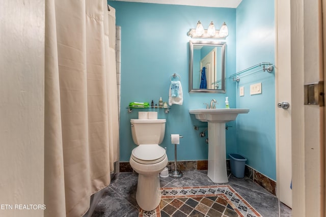 bathroom featuring toilet and curtained shower