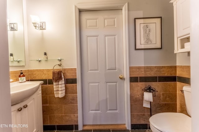 bathroom with toilet, vanity, and tile walls