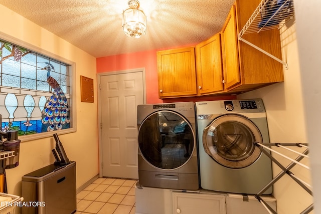 clothes washing area with light tile patterned floors, a textured ceiling, cabinets, and separate washer and dryer