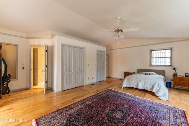 bedroom featuring lofted ceiling, multiple closets, wood-type flooring, and ceiling fan