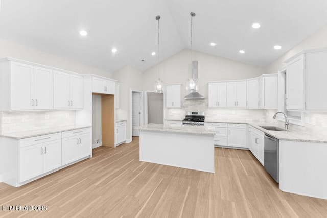 kitchen featuring appliances with stainless steel finishes, wall chimney range hood, a kitchen island, and white cabinets