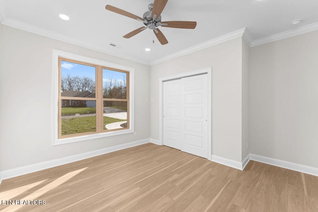 unfurnished bedroom featuring ceiling fan, a closet, crown molding, and light wood-type flooring