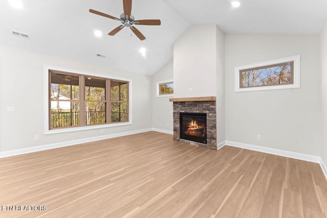 unfurnished living room featuring ceiling fan, high vaulted ceiling, a stone fireplace, and light hardwood / wood-style floors