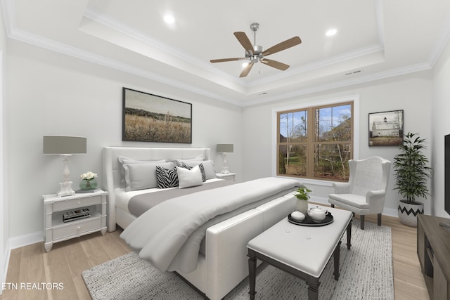 bedroom with light hardwood / wood-style flooring and a tray ceiling