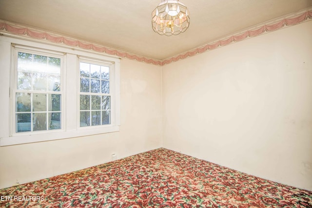 spare room with carpet flooring and a notable chandelier
