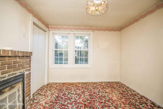 interior space with carpet flooring, a brick fireplace, and a chandelier