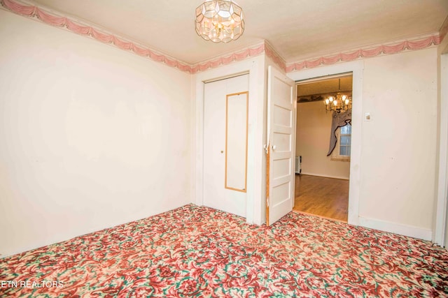 spare room with a notable chandelier and light wood-type flooring