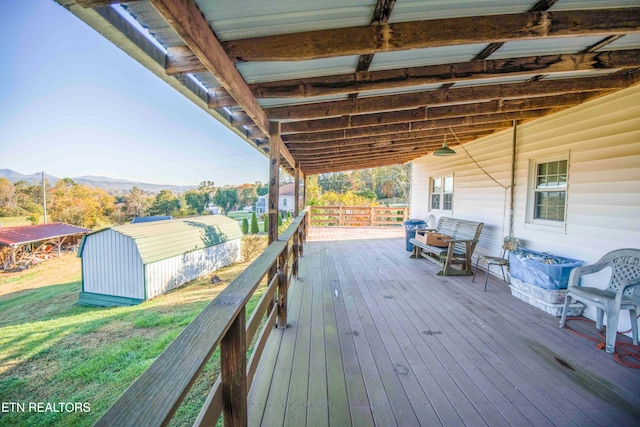 wooden terrace with a mountain view, a storage unit, and a lawn