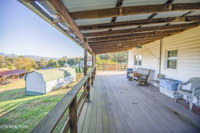 deck with a lawn, an outbuilding, a mountain view, and a storage unit