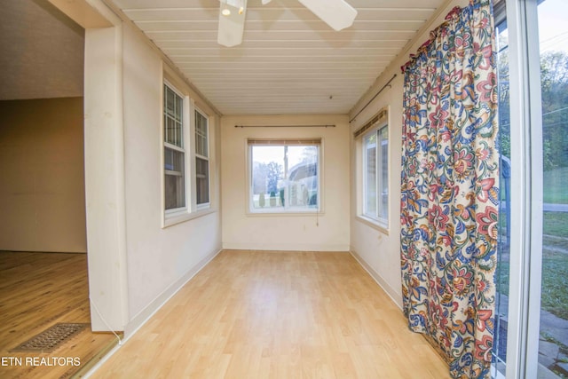 unfurnished sunroom with baseboards, visible vents, and wood finished floors