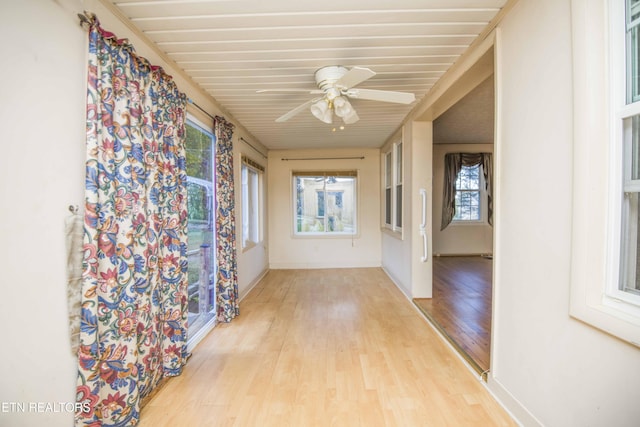 hallway featuring wooden ceiling, baseboards, and wood finished floors