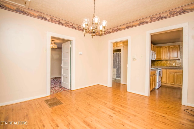 unfurnished dining area featuring a textured ceiling and light wood-type flooring