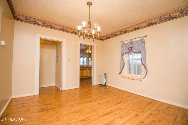 unfurnished room featuring radiator, hardwood / wood-style flooring, a textured ceiling, and ceiling fan with notable chandelier