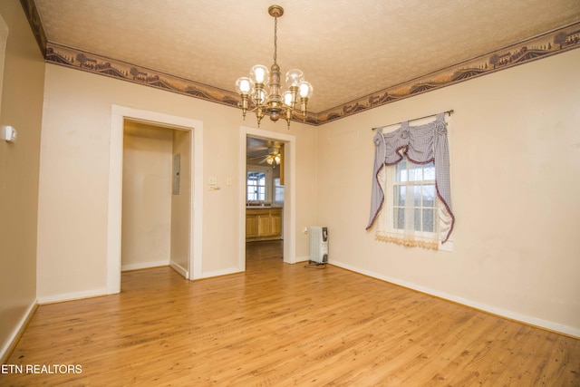 unfurnished room with baseboards, a textured ceiling, wood finished floors, and radiator heating unit