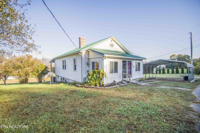 view of front of home with metal roof, a chimney, a front lawn, and a carport