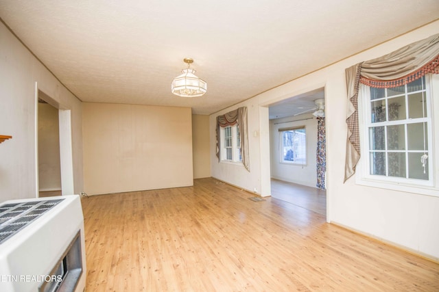 unfurnished room featuring an inviting chandelier and light wood-type flooring