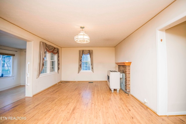 unfurnished living room featuring a textured ceiling, wood-type flooring, and a brick fireplace