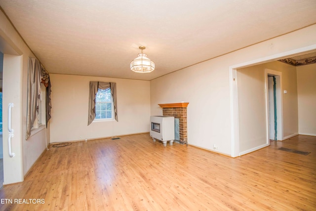 unfurnished living room featuring light hardwood / wood-style floors, a textured ceiling, and a fireplace