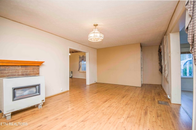 unfurnished living room with light hardwood / wood-style flooring and a textured ceiling