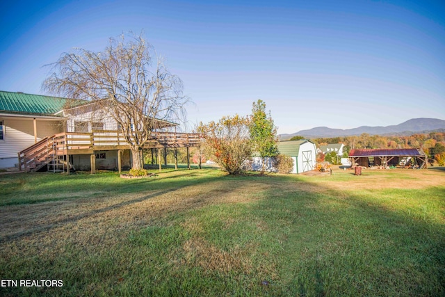 view of yard with a deck with mountain view and a shed