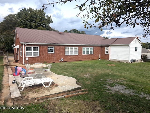 1005 Monroe St, Sweetwater, TN 37874 - back of house featuring brick siding, a patio area, a lawn, and metal roof