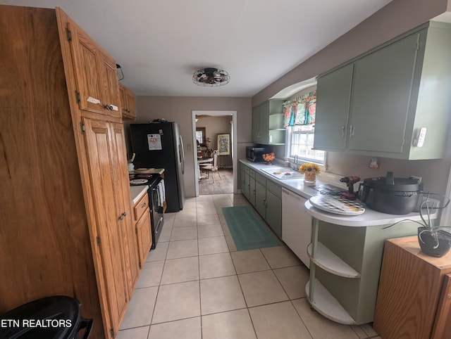 kitchen with dishwasher, light tile patterned flooring, black / electric stove, and sink