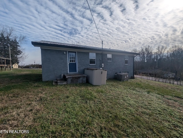 rear view of property with a lawn and central AC unit