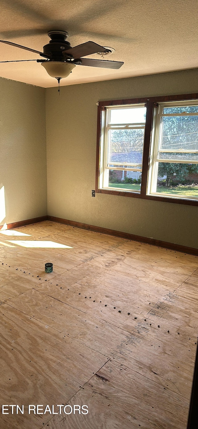 unfurnished room with a textured ceiling, light wood-type flooring, and ceiling fan