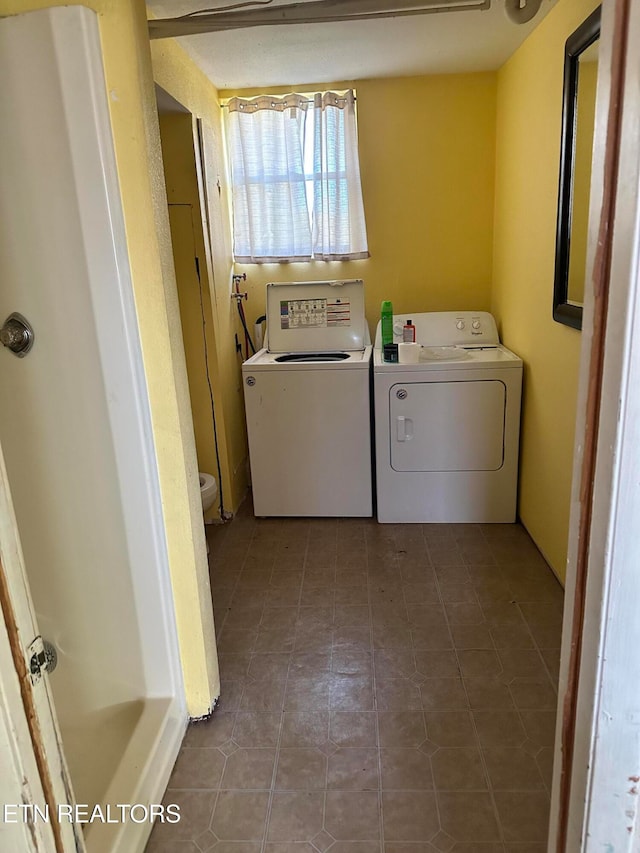 clothes washing area with washer and dryer and dark tile patterned floors