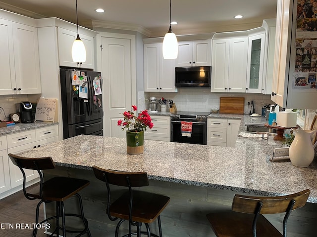 kitchen with dark wood-type flooring, stainless steel appliances, hanging light fixtures, and white cabinets