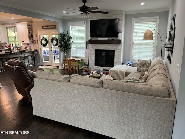 living room featuring french doors, a stone fireplace, ceiling fan, ornamental molding, and dark hardwood / wood-style floors