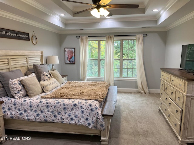 carpeted bedroom with ornamental molding, a tray ceiling, and ceiling fan