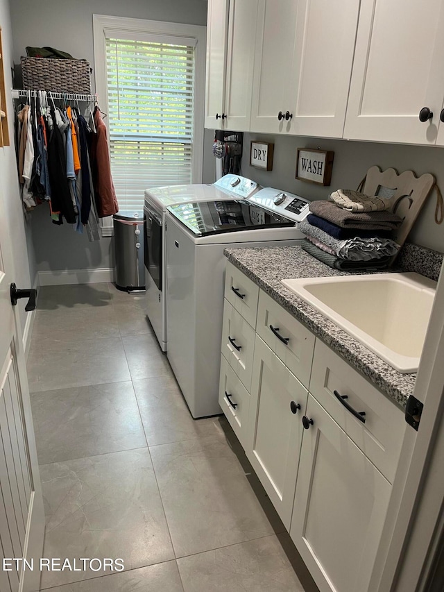 washroom featuring sink, light tile patterned flooring, washing machine and dryer, and cabinets