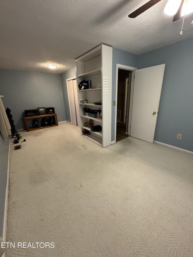 basement with ceiling fan, carpet floors, and a textured ceiling