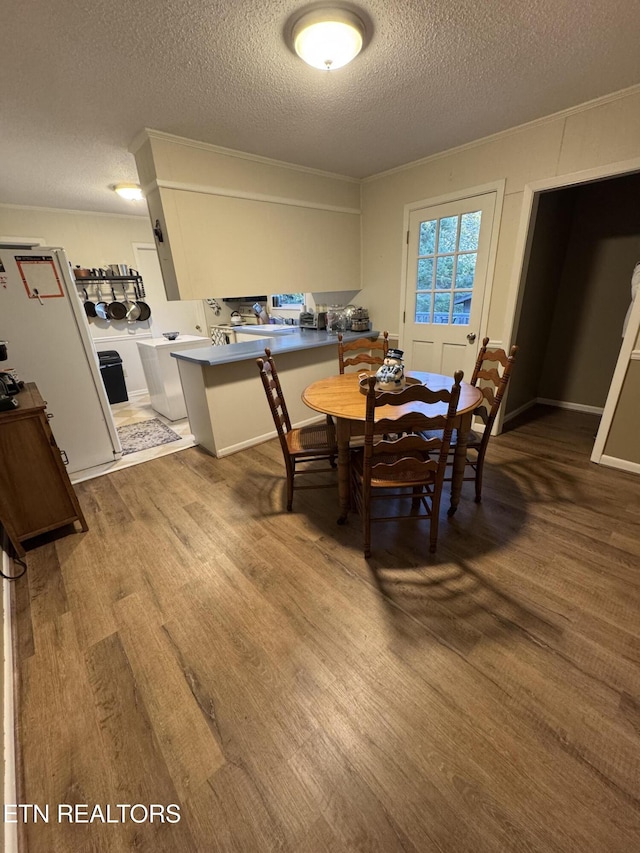 dining room featuring dark hardwood / wood-style flooring, ornamental molding, and a textured ceiling