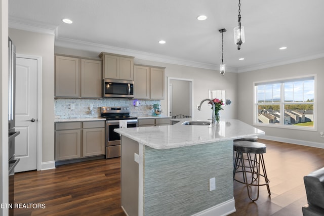 kitchen featuring appliances with stainless steel finishes, sink, pendant lighting, dark hardwood / wood-style floors, and a kitchen island with sink