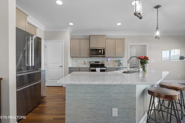 kitchen featuring sink, stainless steel appliances, decorative light fixtures, dark wood-type flooring, and a center island with sink