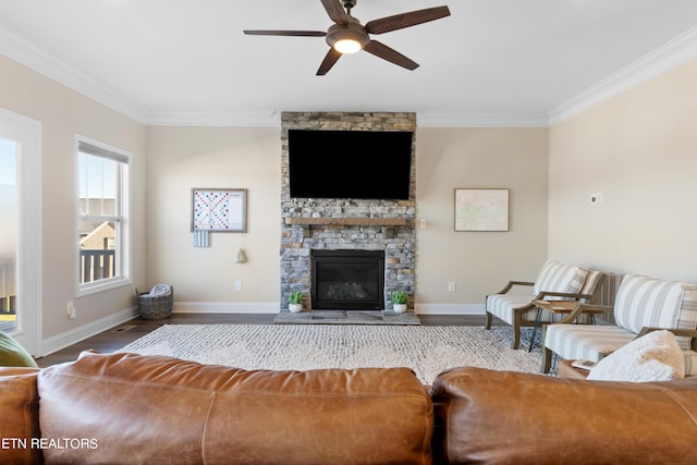 living room with hardwood / wood-style flooring, a stone fireplace, crown molding, and ceiling fan