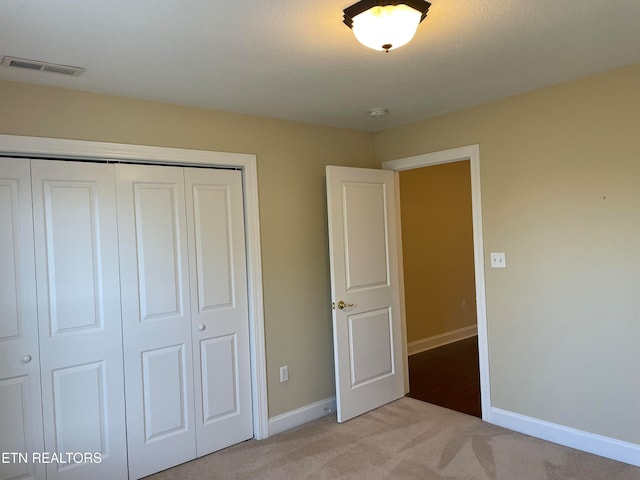 unfurnished bedroom with a closet and light colored carpet