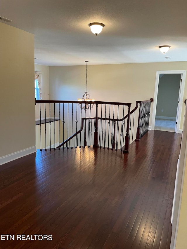 empty room featuring dark hardwood / wood-style floors and a chandelier