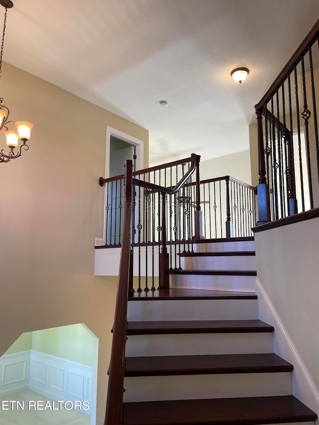 stairway featuring a chandelier