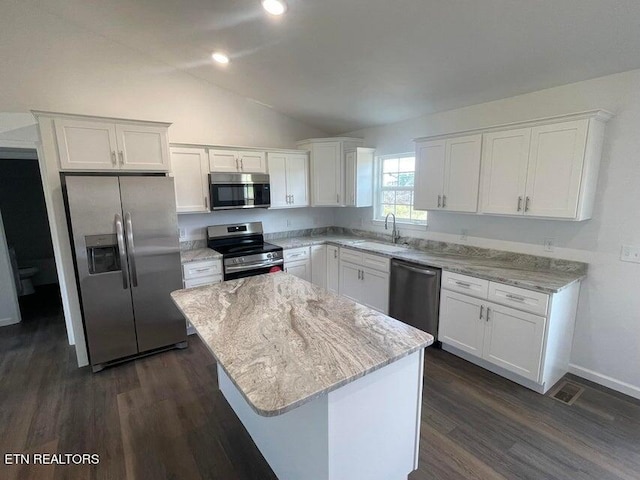 kitchen featuring lofted ceiling, appliances with stainless steel finishes, white cabinetry, sink, and a center island