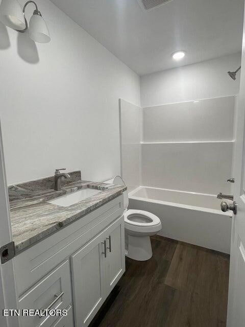 full bathroom featuring toilet, vanity, wood-type flooring, and shower / bathtub combination