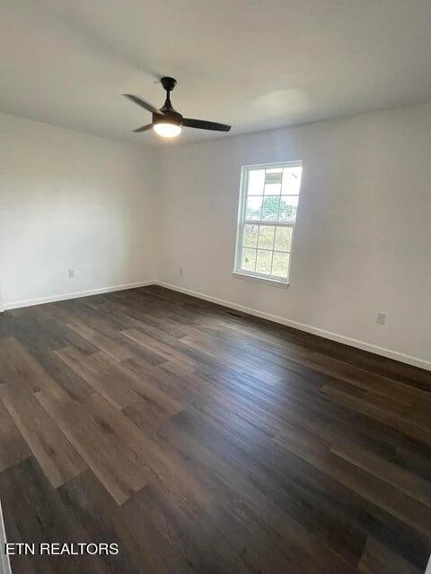 empty room featuring dark wood-type flooring and ceiling fan