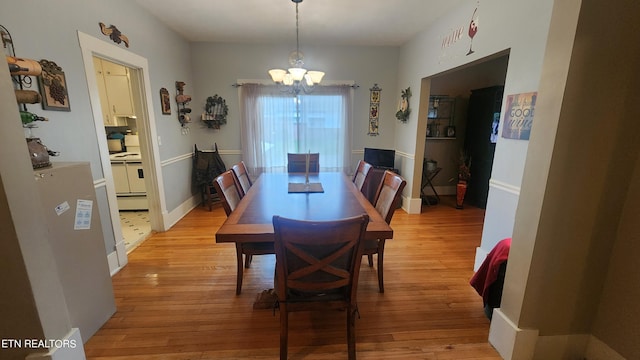 dining room with light hardwood / wood-style flooring and an inviting chandelier